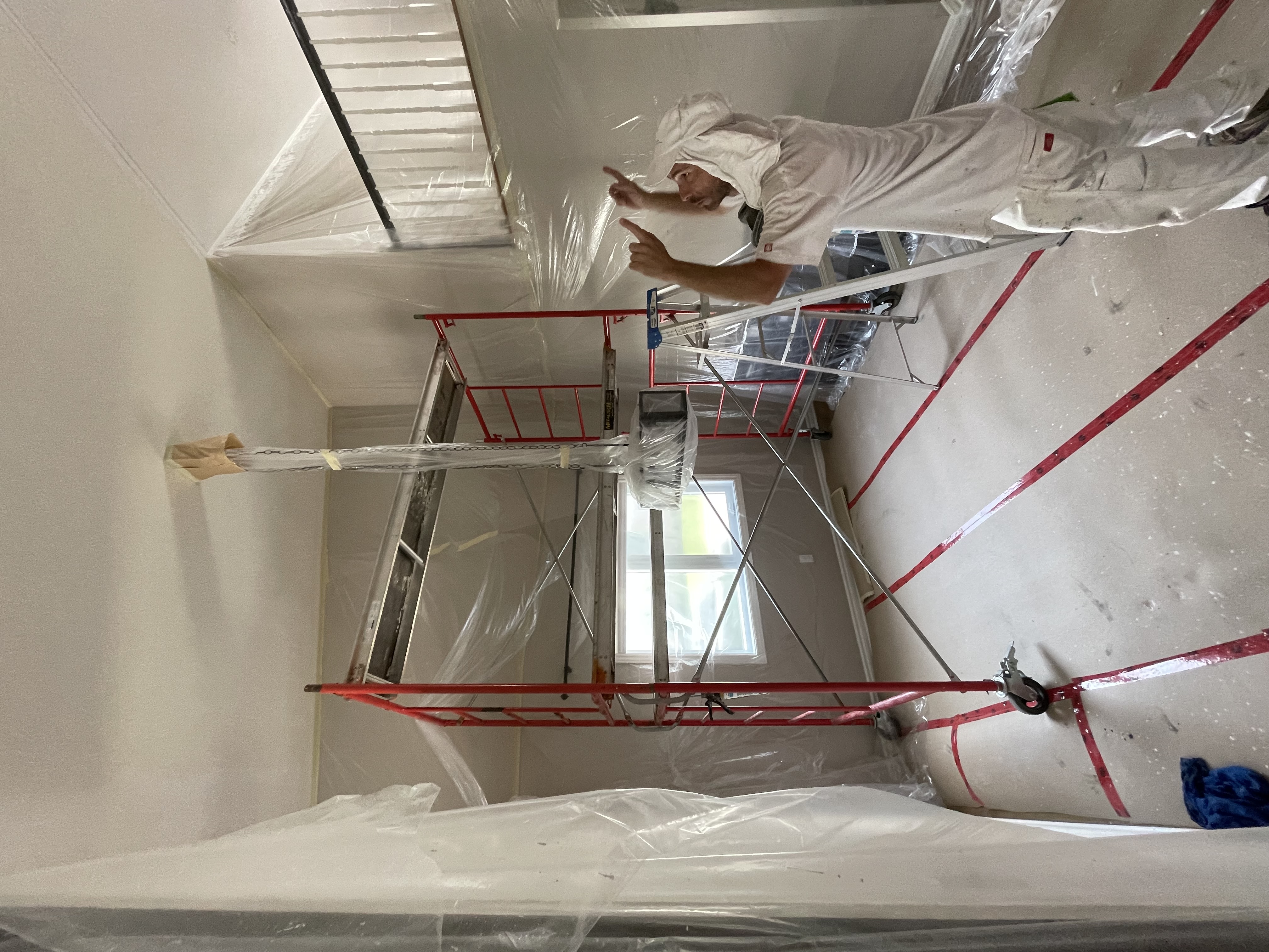 Painter working from scaffold with full plastic sheeting protection