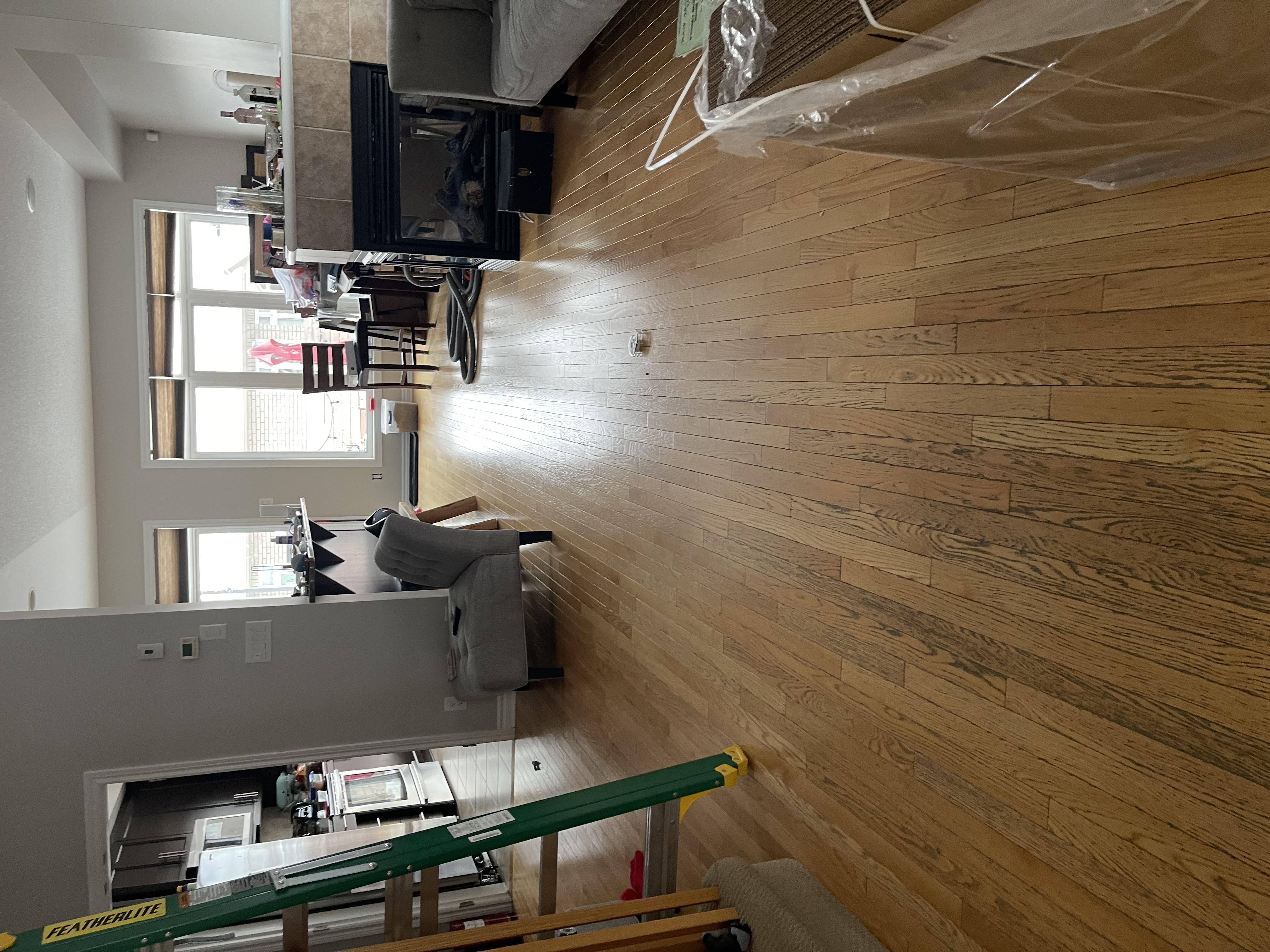Open-concept hardwood floor and kitchen area during finishing work