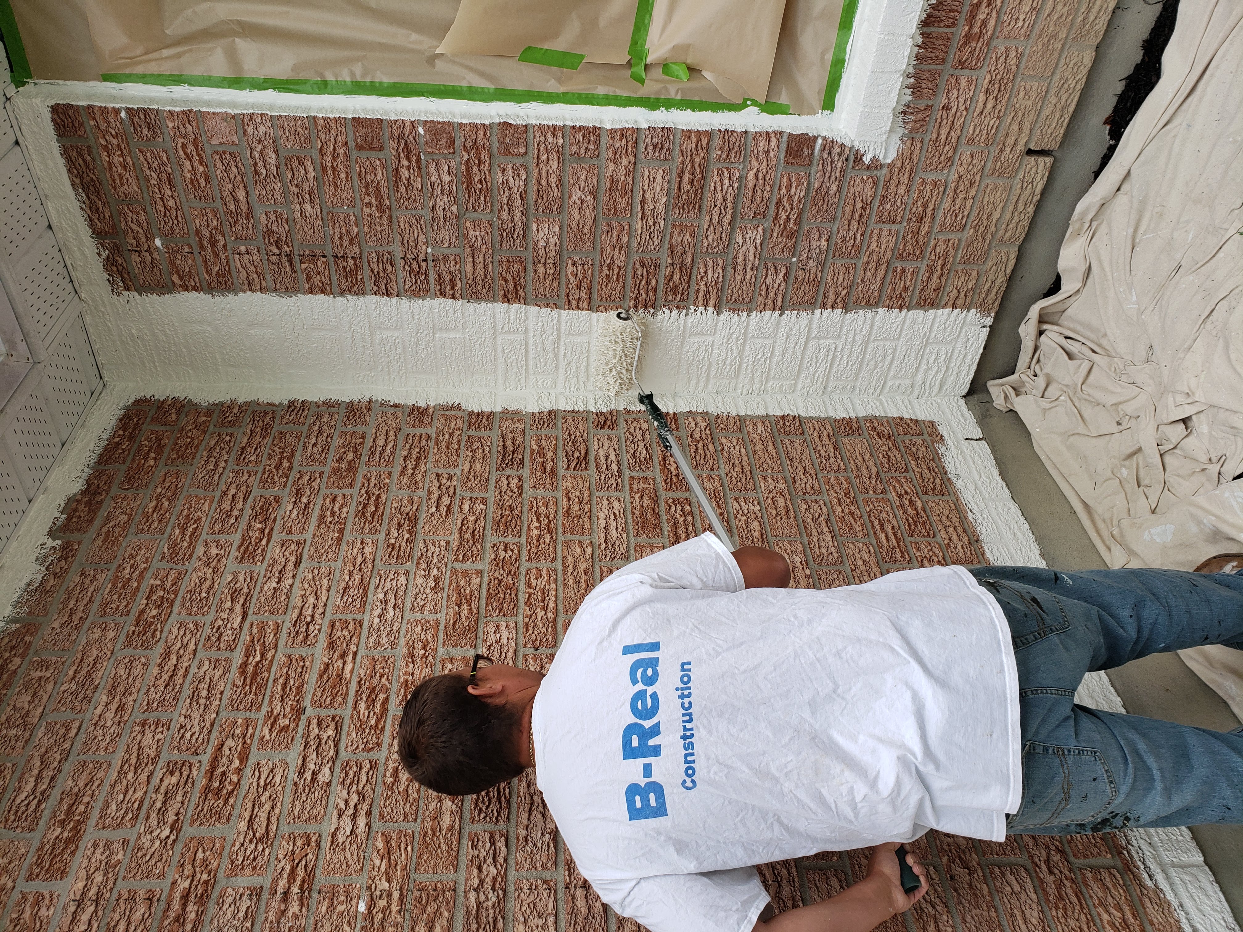 Painter rolling coating onto a brick corner elevation